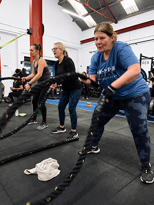 Members working on battle ropes during a group class