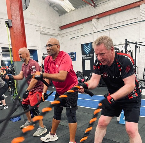 Members training with battle ropes during a full body HIIT class