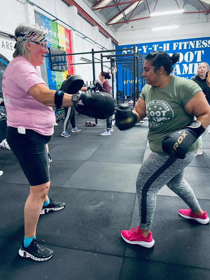 Two women practising boxing combinations with gloves and focus pads
