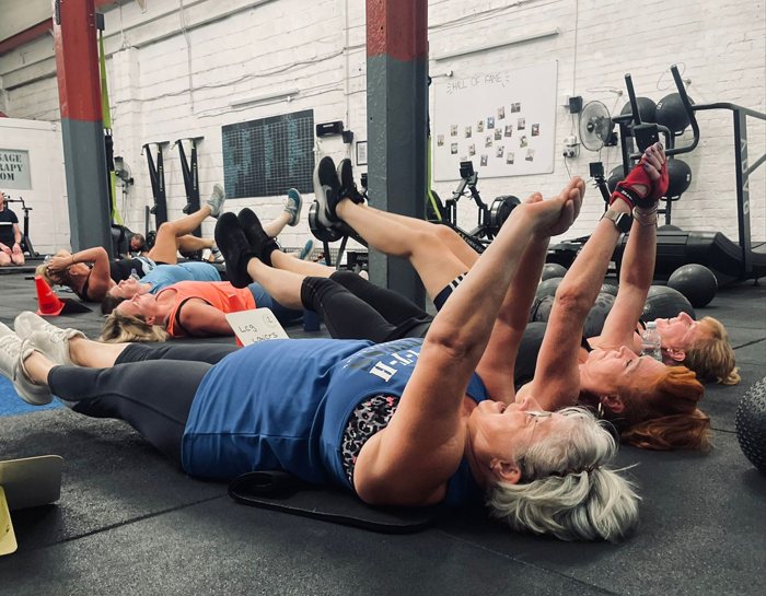 Group of members doing core exercises on mats during a core and cardio class