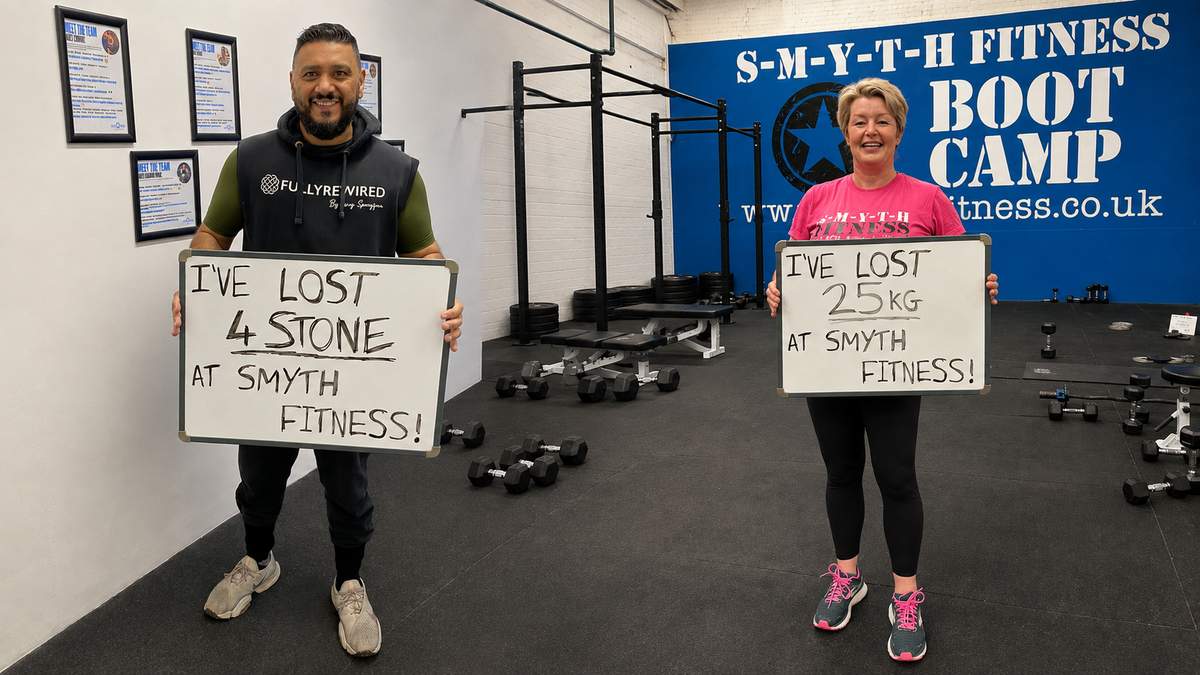 Two Smyth Fitness members holding signs celebrating how much weight they have lost